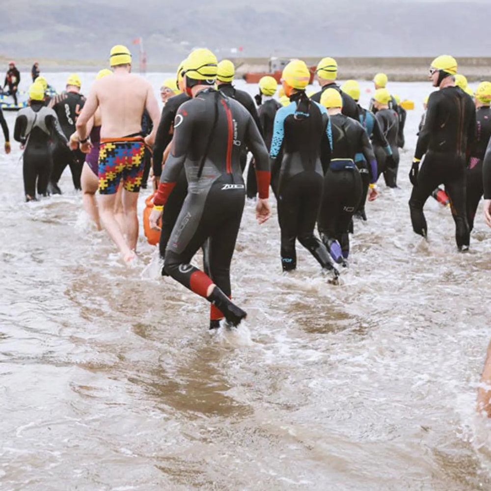 A group of people entering the sea to go swimming