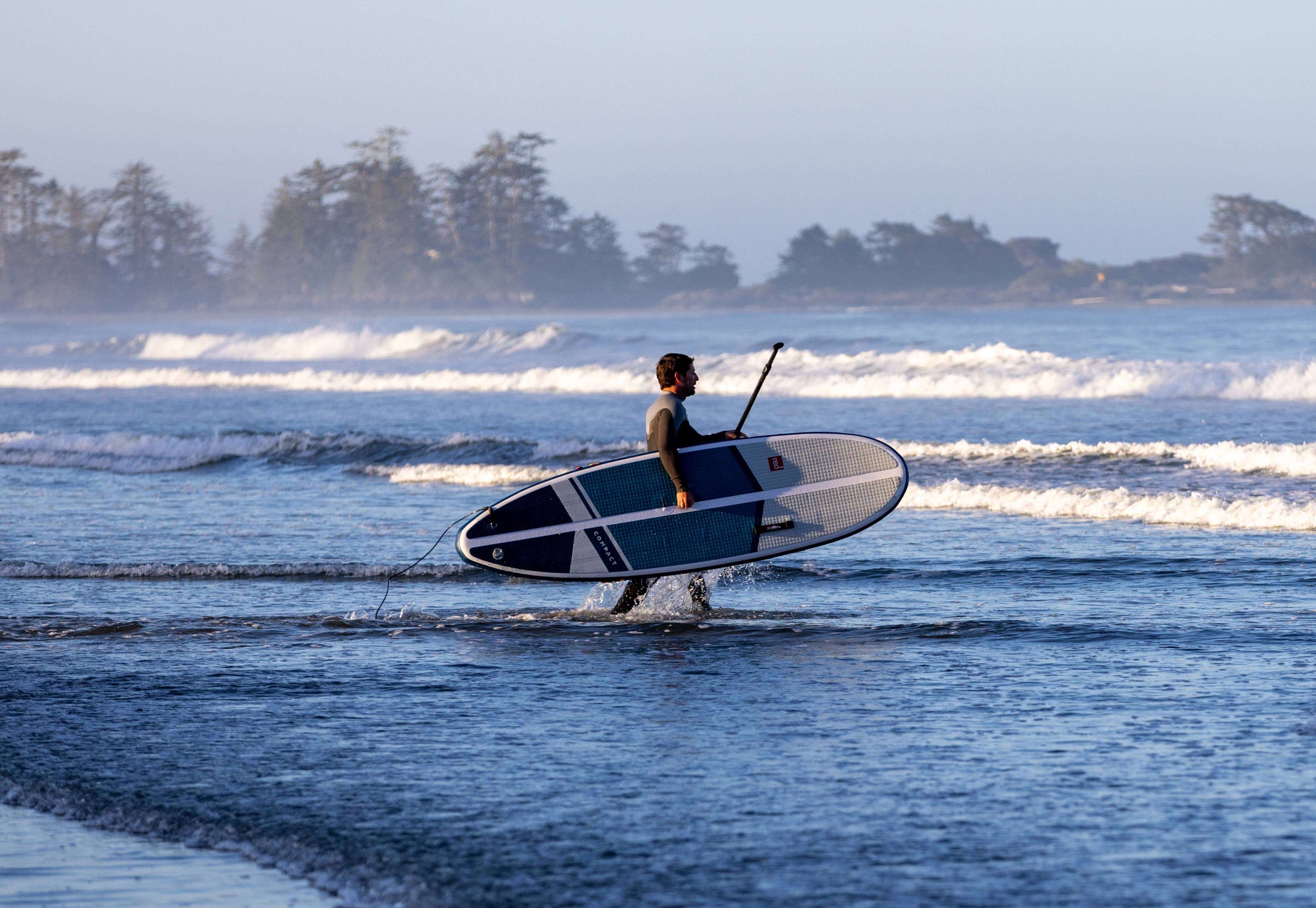 man entering the sea with inflatable paddleboard on his own