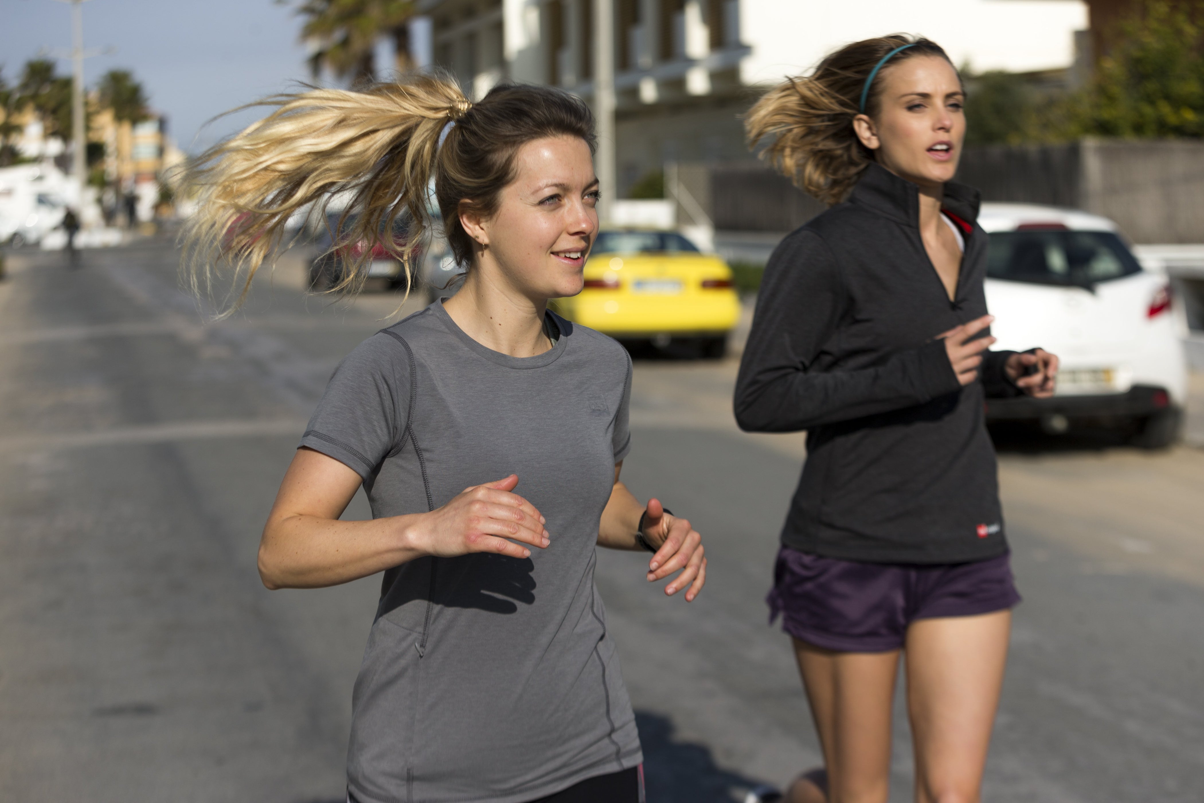 women running in street wearing red originals gear