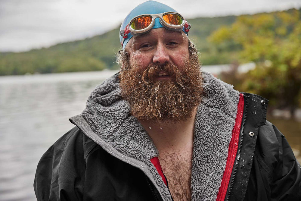 bearded man wearing a swim cap, goggles and waterproof changing robe