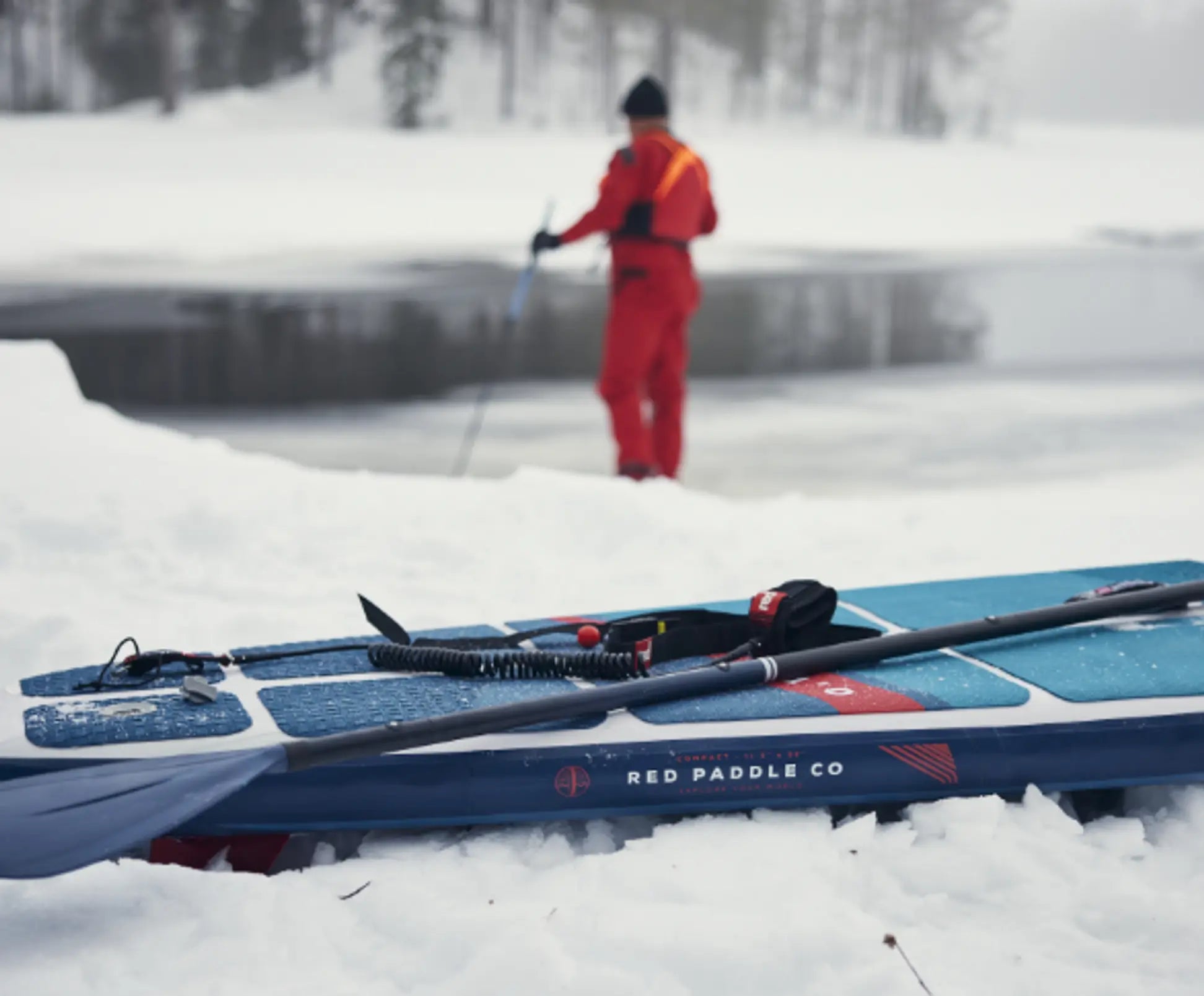 A paddleboard in the snow with a person walking in front