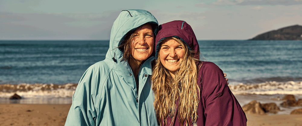 two women wearing red pro change robe on beach