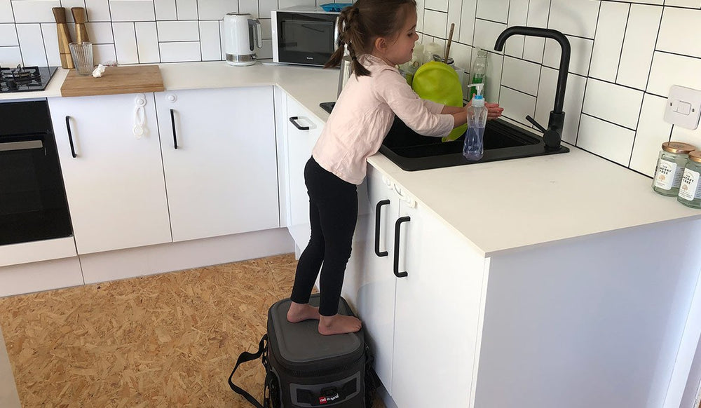 red original cooler bag being used as a kids stool