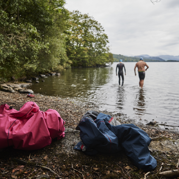 Two men with Red Pro Change Robes walking into the water to go swimming