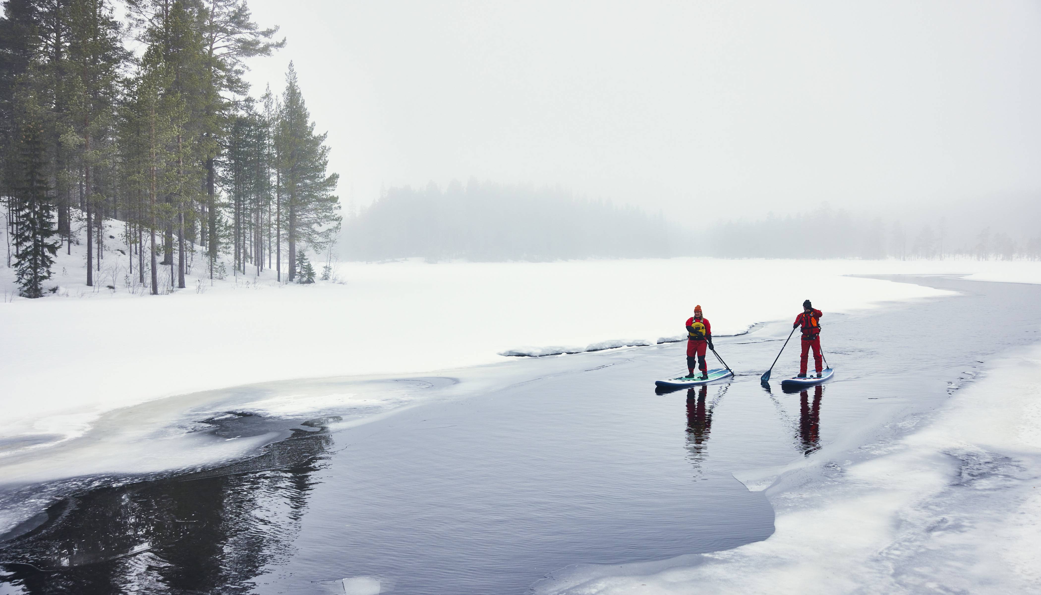 Two people paddling on Red Paddle Co Paddleboard in snow and ice