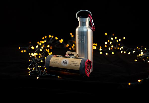 An insulated water bottle and microfibre towel surrounded by fairy lights