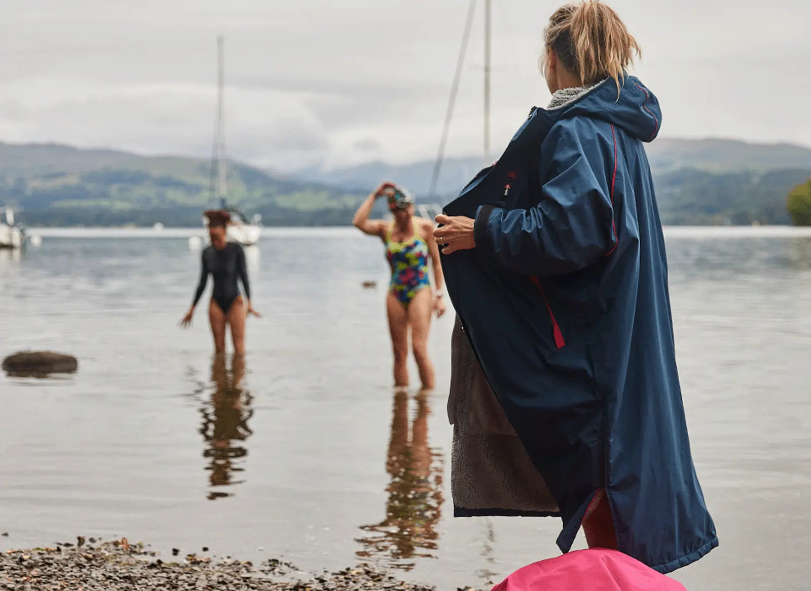 A woman wearing her Red's Womens Pro Change Robe and 2 women paddling in the sea