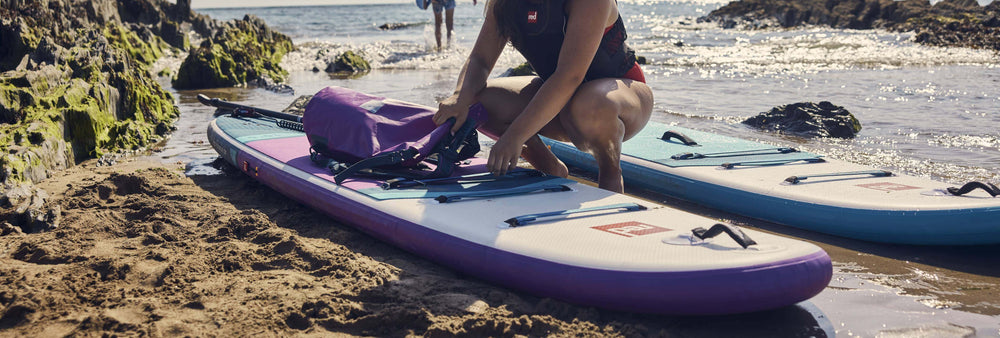 person bending down to adjust inflatable paddleboard