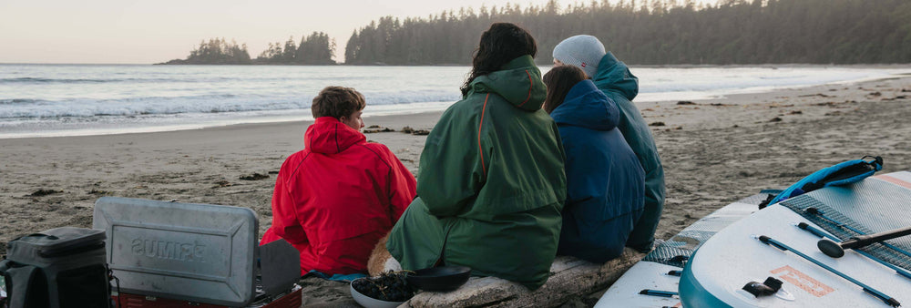 family sat on the beach wearing changing robes