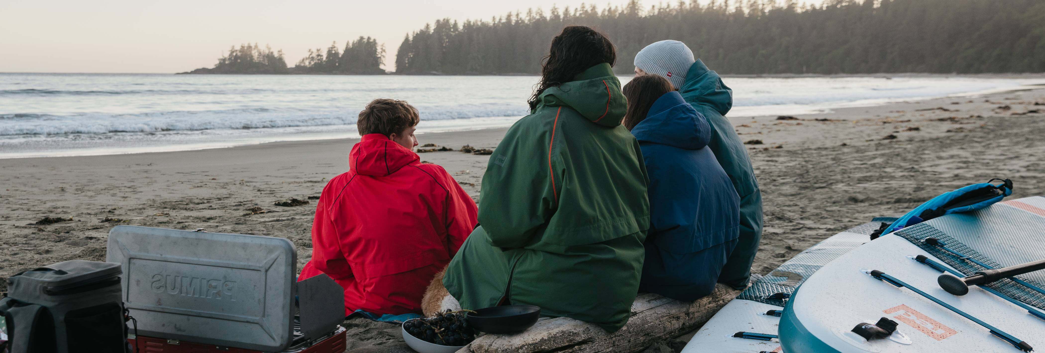 family sat on the beach wearing changing robes