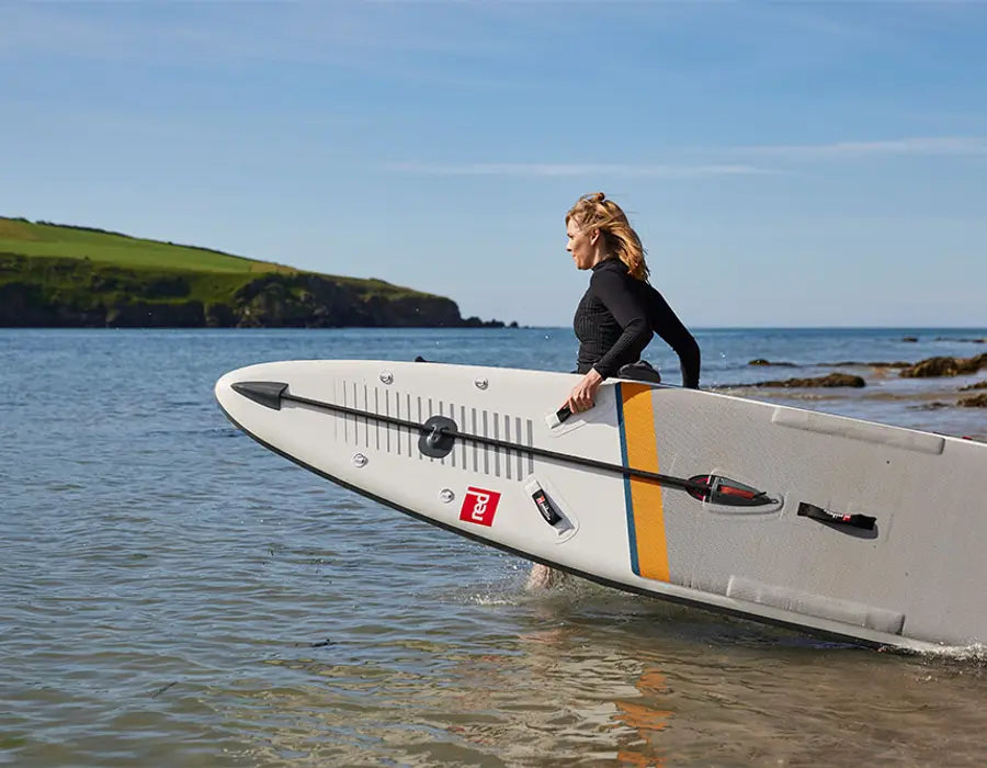 Woman carrying her paddleboard into the ocean