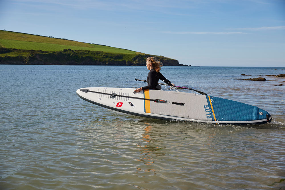 Woman carrying Red Original SUP into the sea