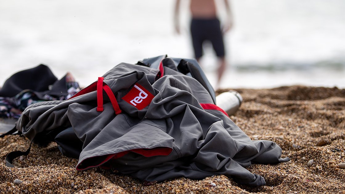 Grey Microfibre changing robe on the beach with man in the background walking toward the sea