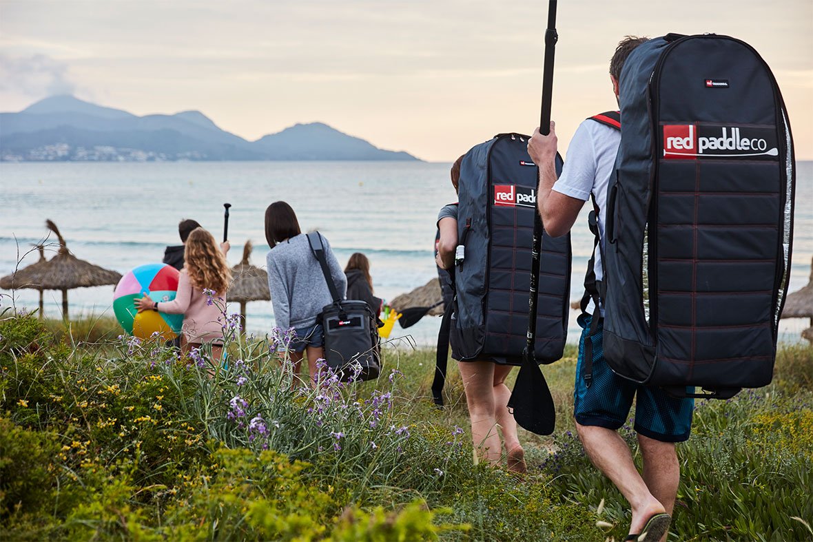 people walking to the beach with red original backpacks and gear