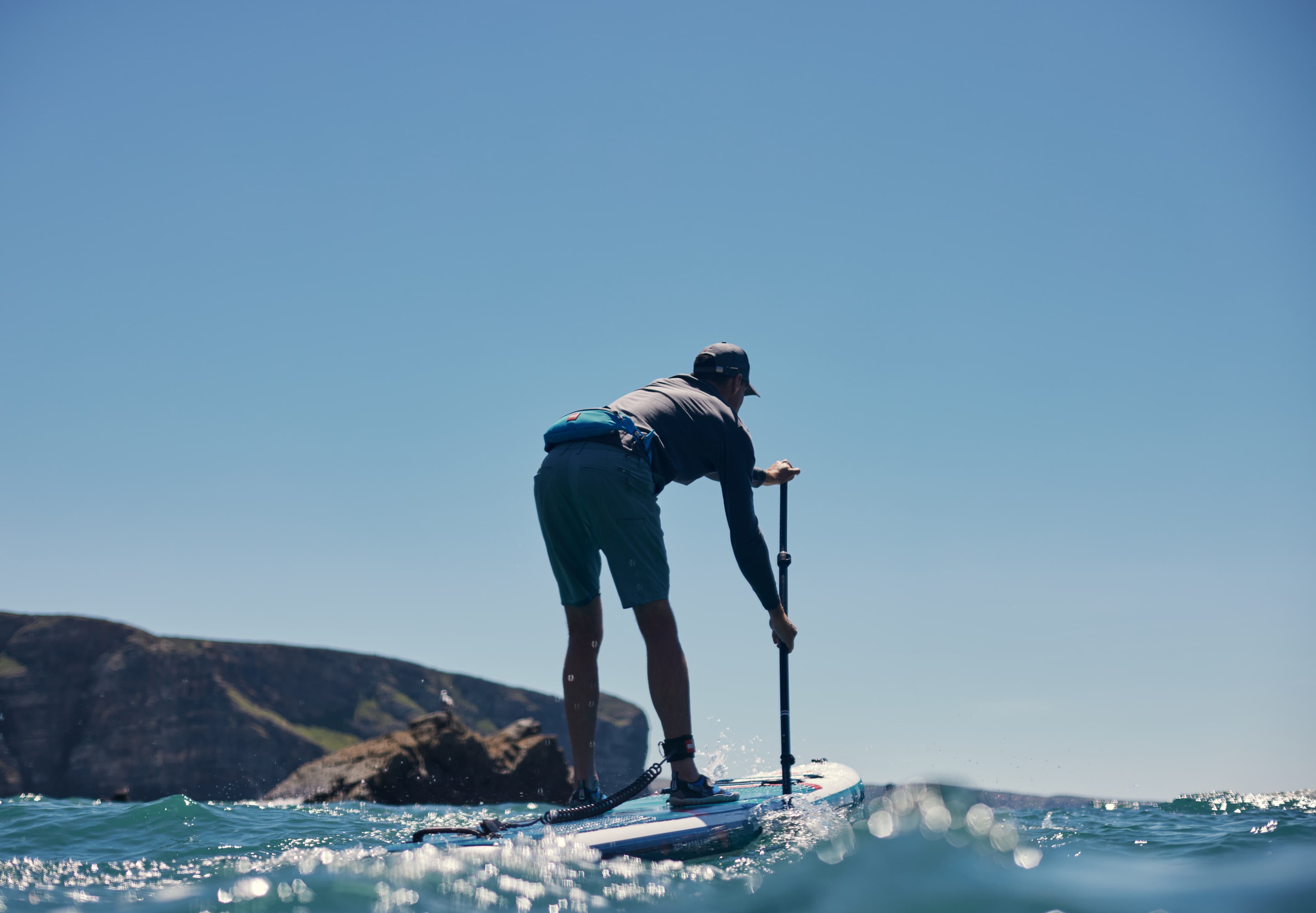 rear angle of a man on a paddleboard in the ocean