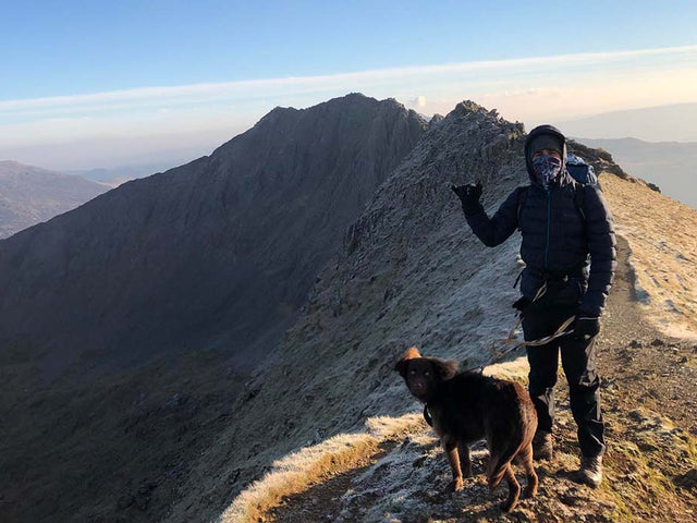 Man and a dog standing at the top of a mountain