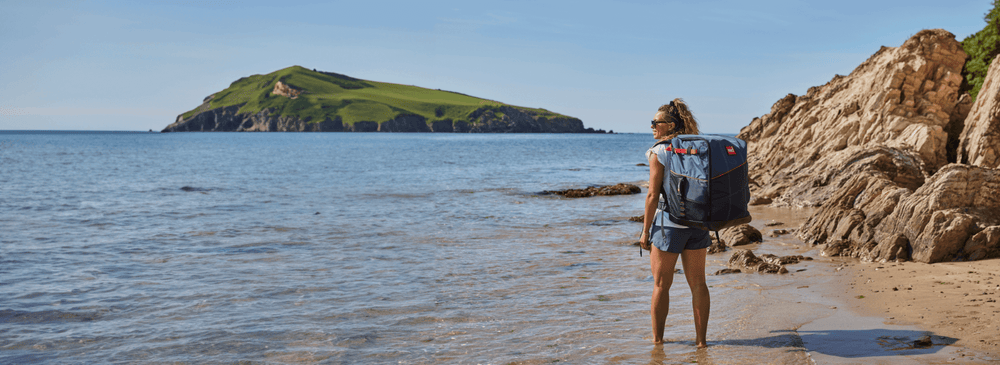 woman on the beach with paddleboard bag on back