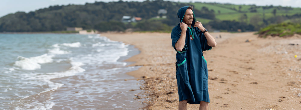 A man wearing the Red Quick Change Robe on a beach