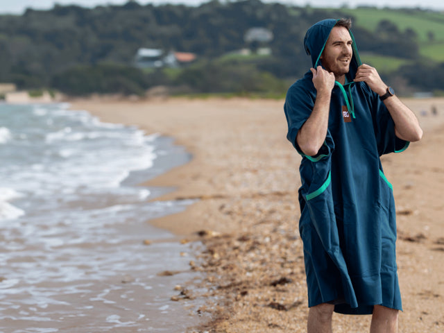 A man wearing the Red Quick Change Robe on a beach
