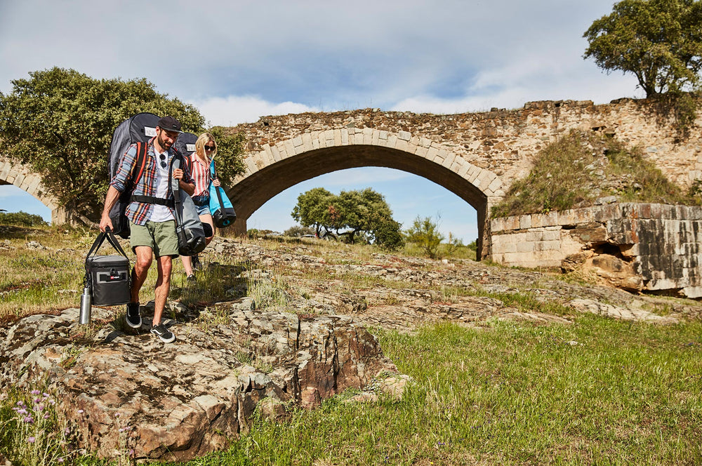 Man and Woman Walking Near A Bridge Carrying Red Original Outdoor Accessories