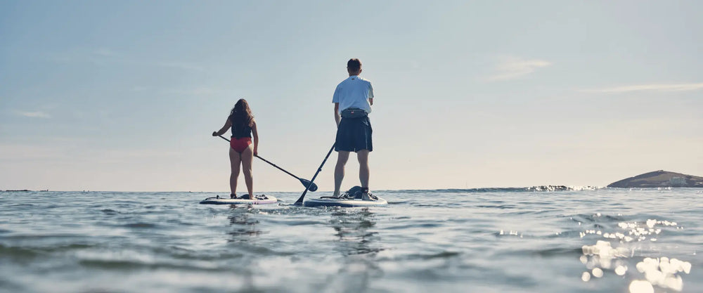 two people paddleboarding towards horizon