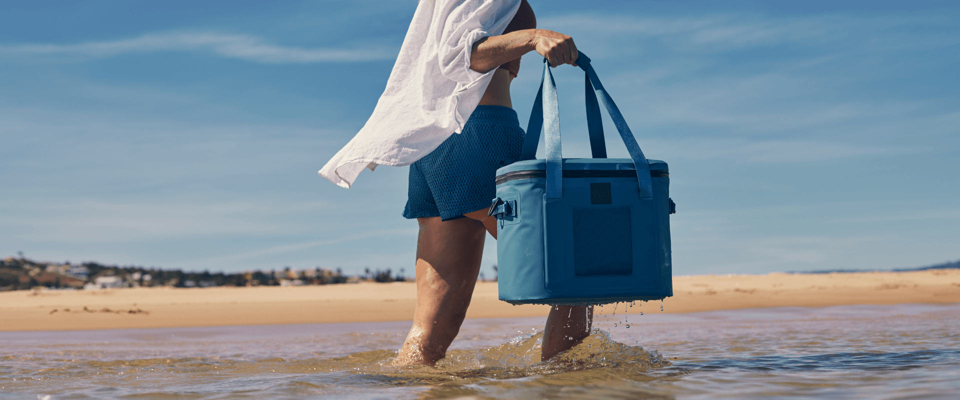 man carrying waterproof soft cooler bag through water