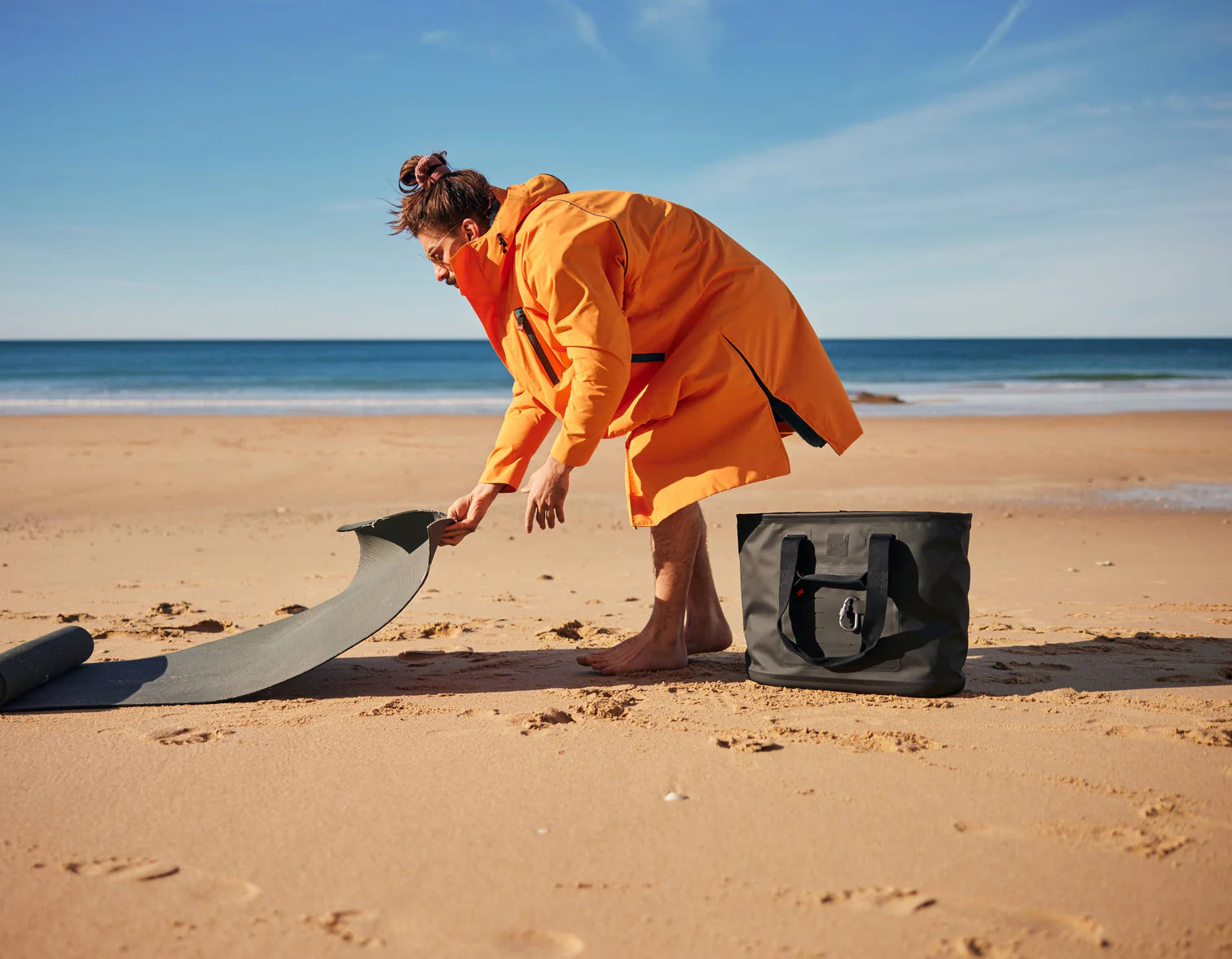 A person on the beach laying out their yoga mat wearing the alter evo robe