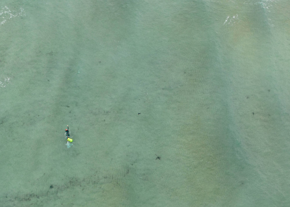 a zoomed out aerial shot of a swimmer in open water