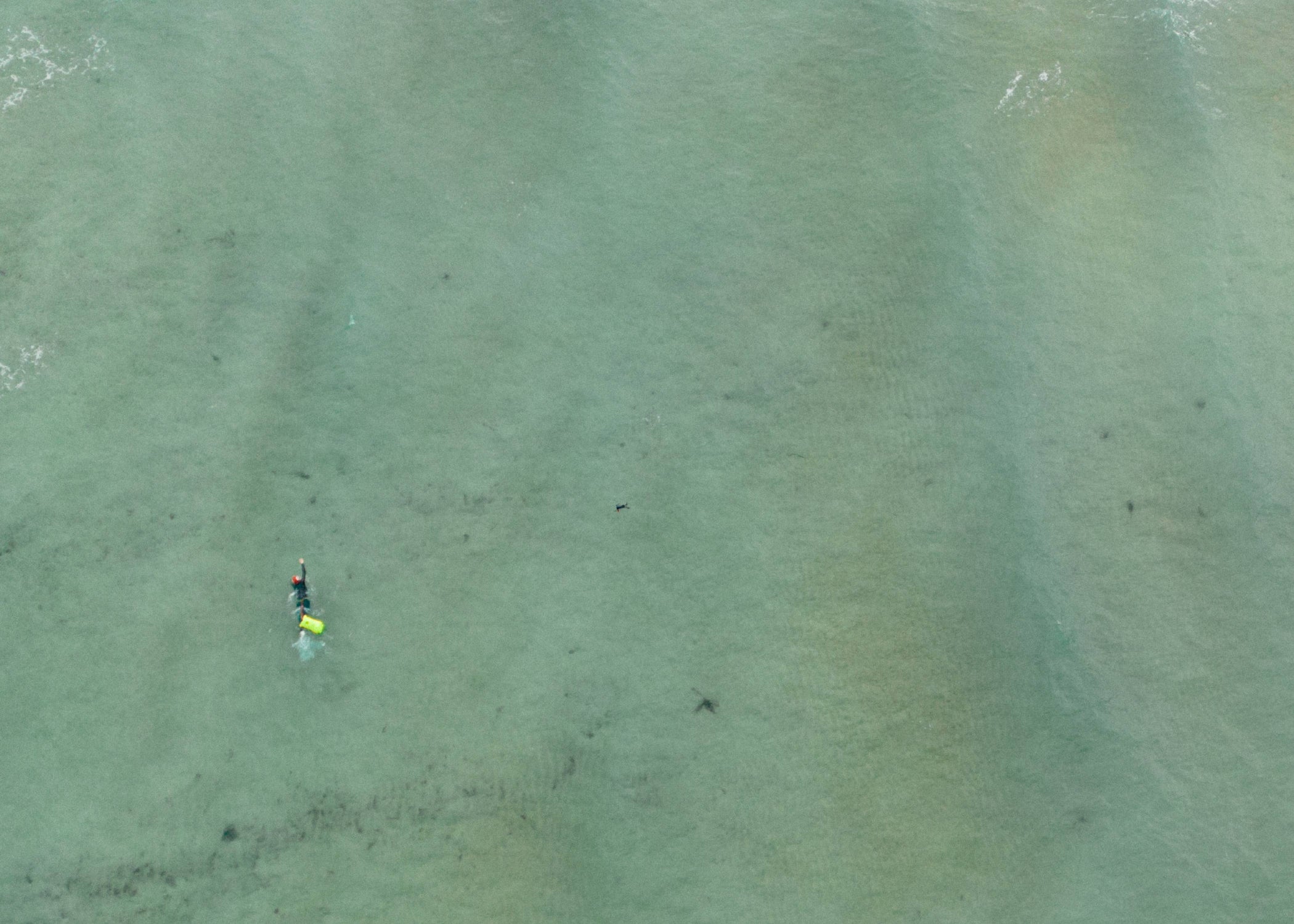 a zoomed out aerial shot of a swimmer in open water