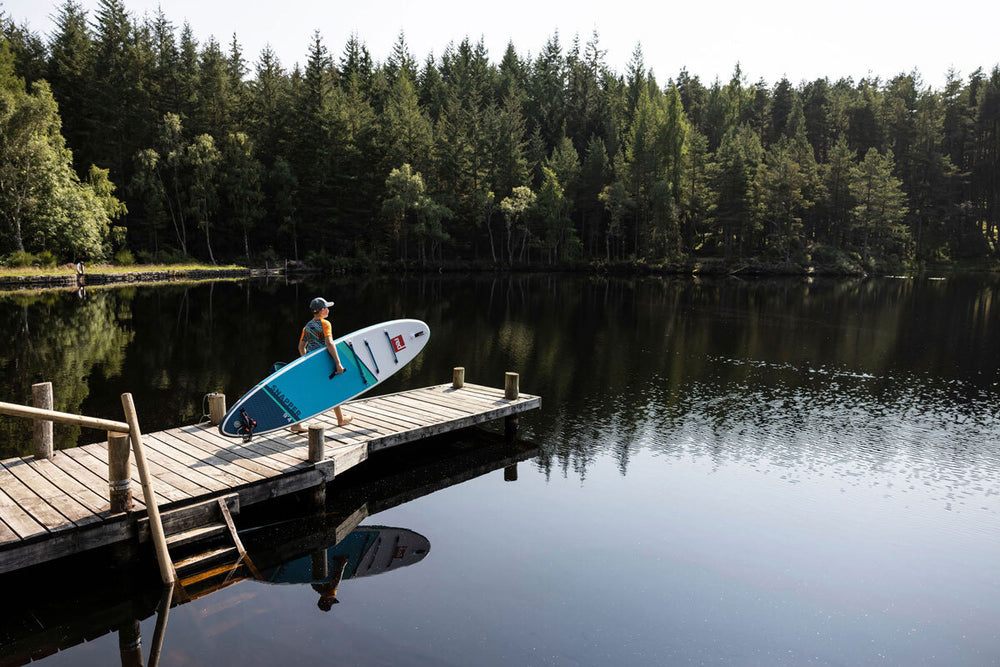 Paddle Boarder walking toward a Lake