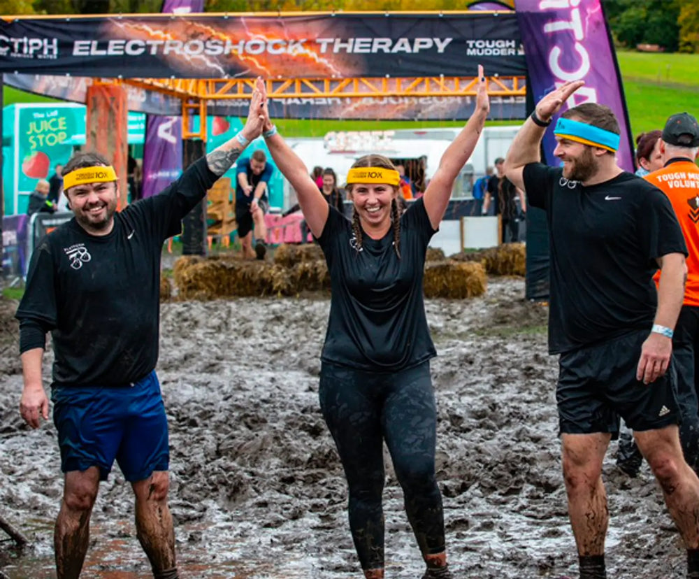 3 people with their arms in the air in the mud