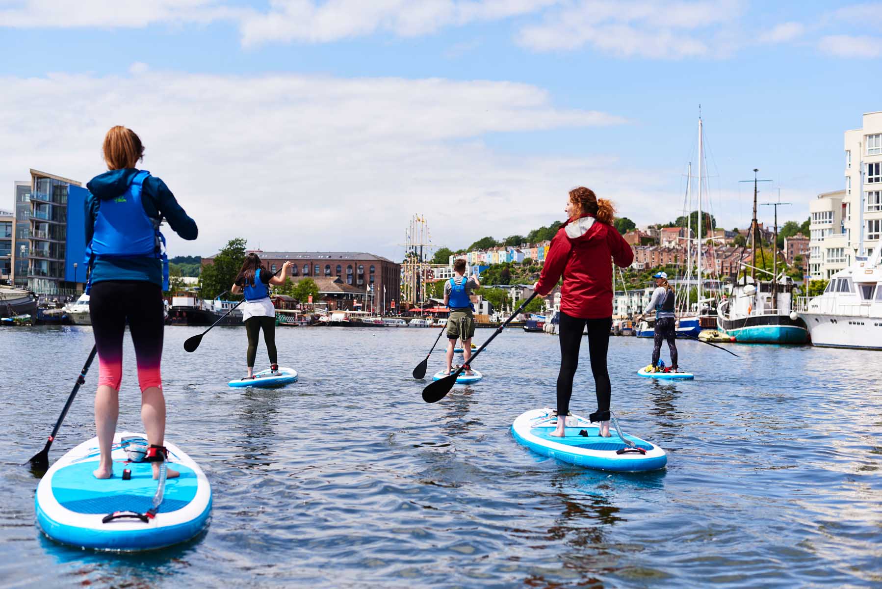 Multiple people paddle boarding in Bristol Harbour