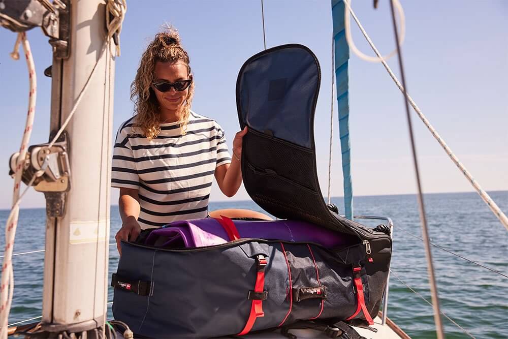 woman storing paddle board in board bag on the deck of a boat