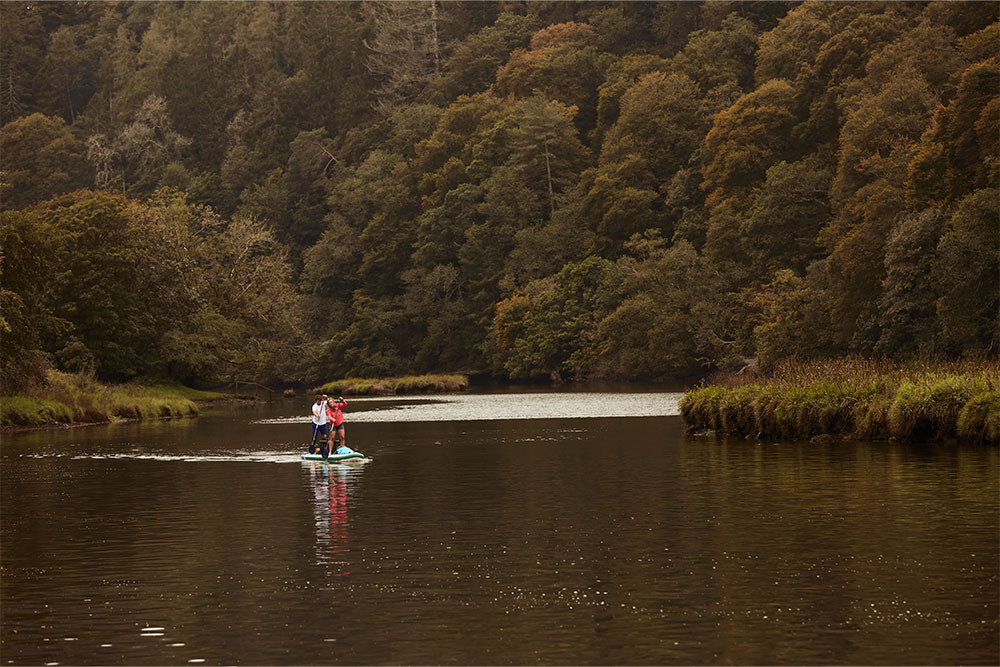 couple paddling on a lake surrounded by woodland