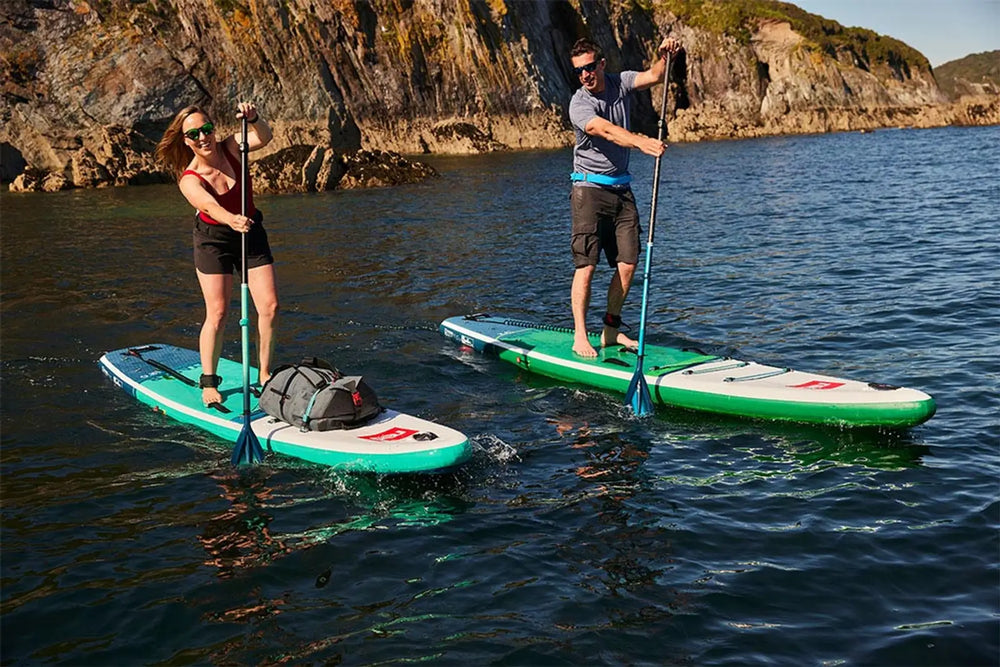 2 people paddleboarding in the ocean, laughing