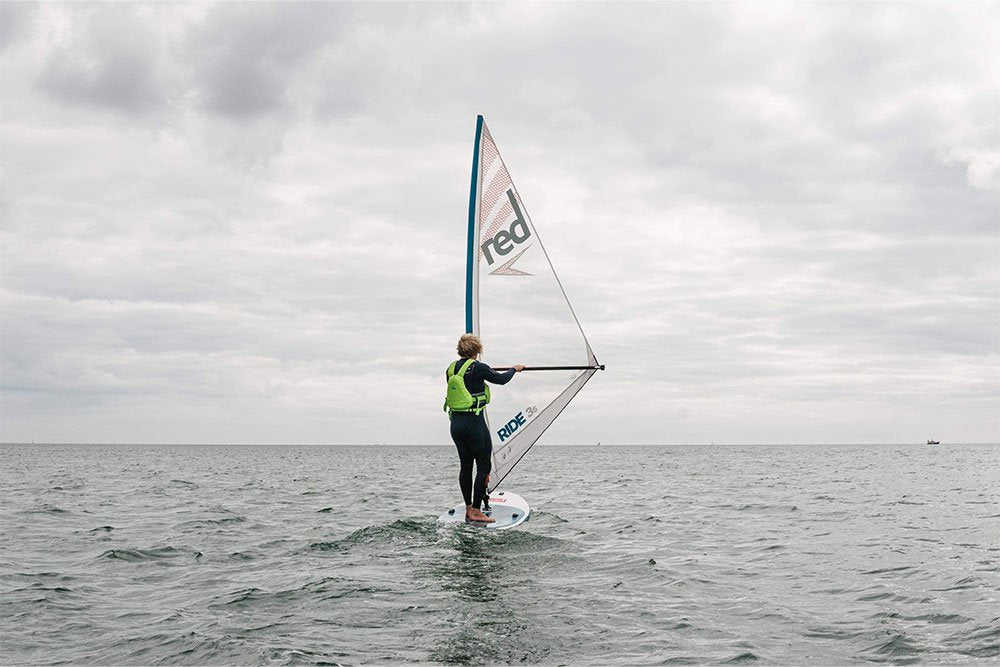 Man paddle boarding in the sea using Red Original Windsurf MSL paddle board