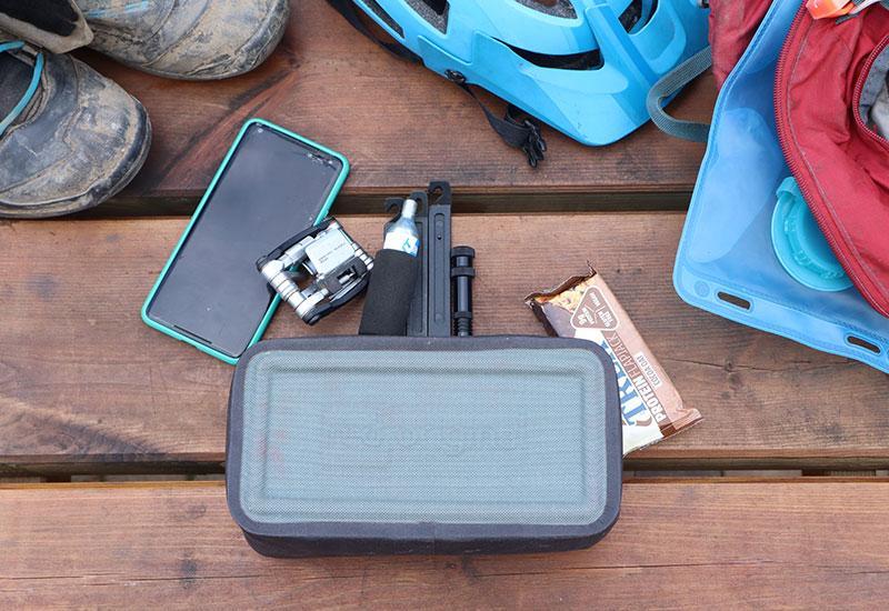 Red Original Waterproof Pouch on decking surrounded by items