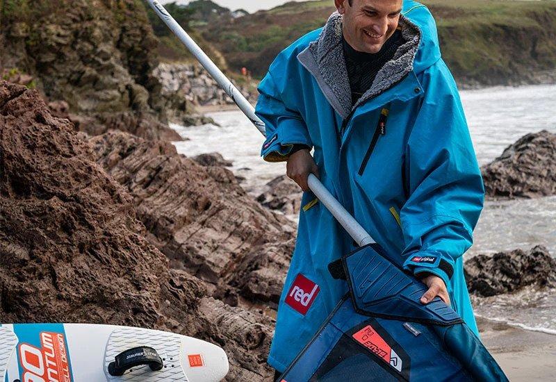 Prepping a WindSUP while wearing a blue short sleeve Waterproof changing robe