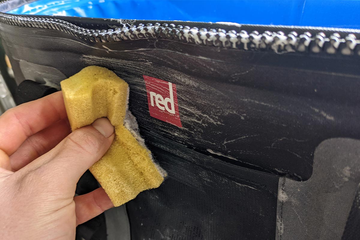 Cleaning the front of the Red Original Cooler Bag With A Sponge