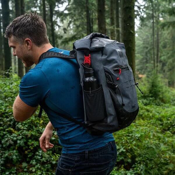 man wearing Red Original Waterproof Backpack whilst walking through a woodland area