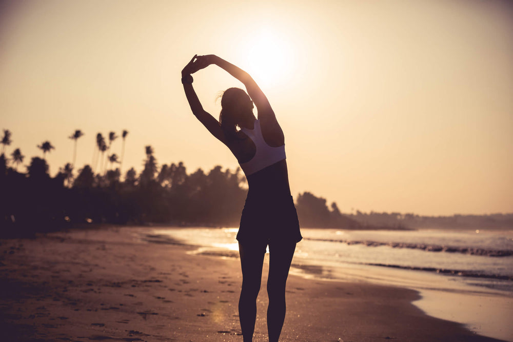 woman stretching on beach at sun rise