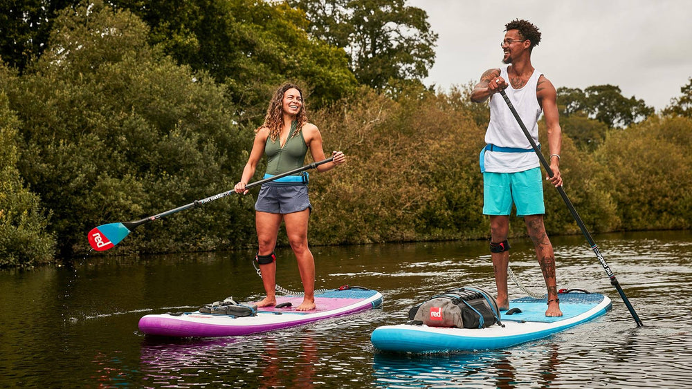 two people paddling alongside each other on Red inflatable paddle boards