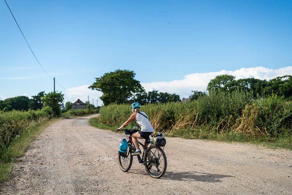 Woman Bikepacking down a gravel road