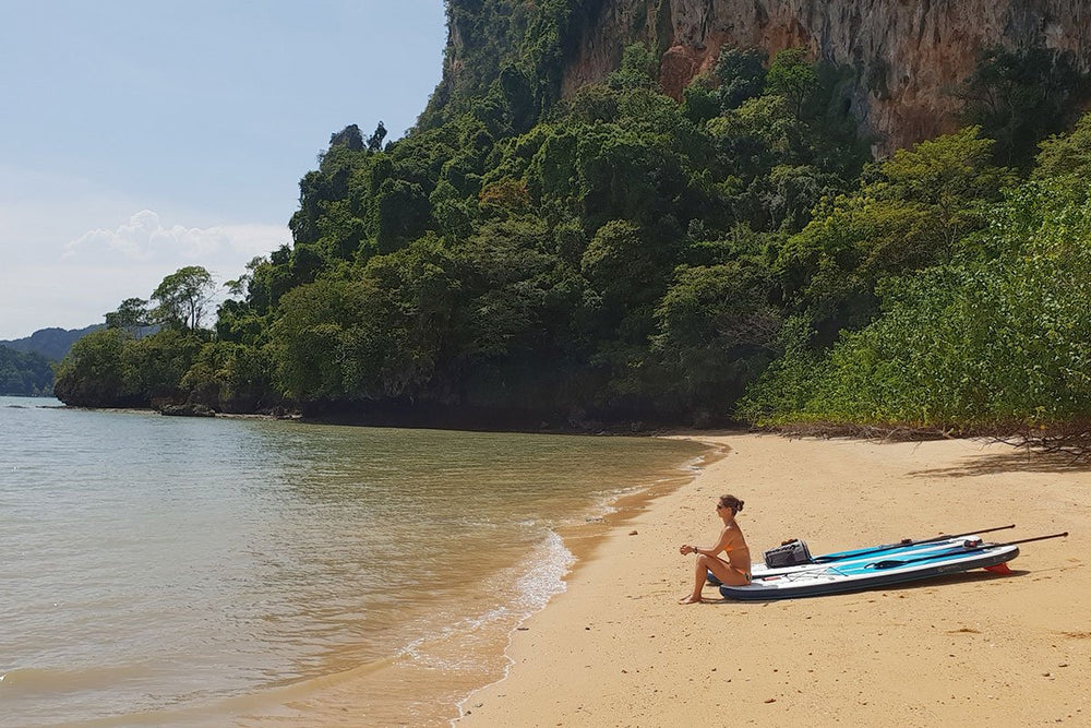 Woman On A Beach sat by her Paddle Board