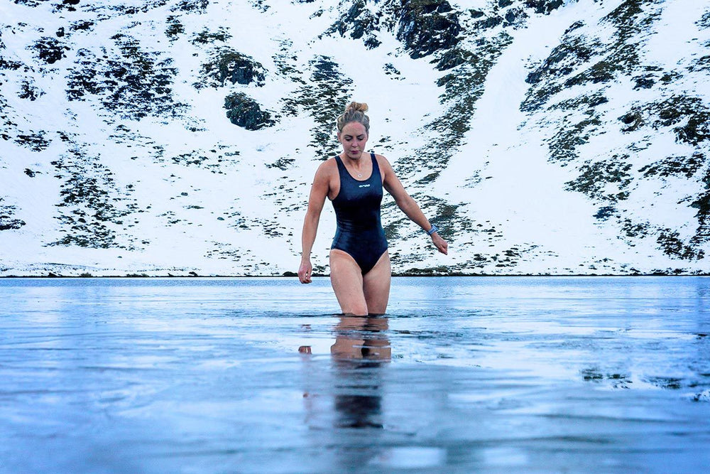 Woman walking into an icy lake on a snowy day