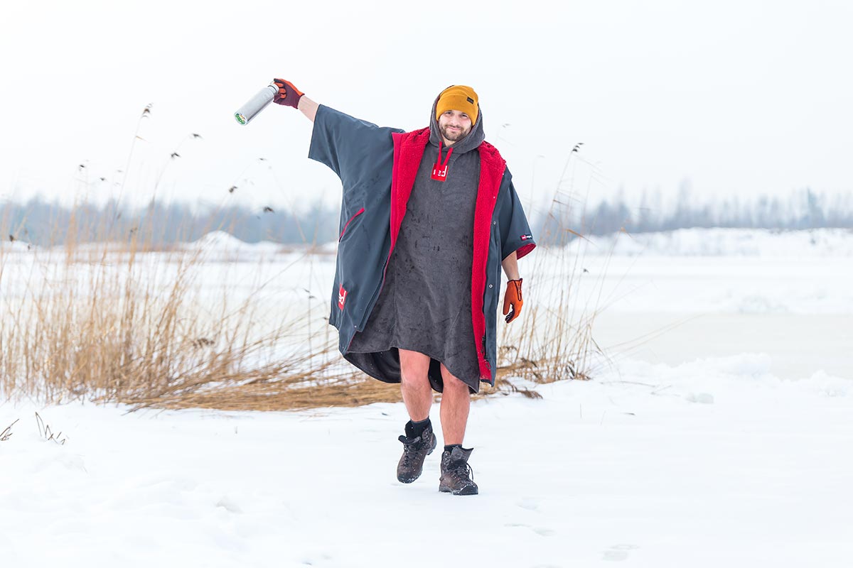 Man in a changing robe walking on a snowy beach