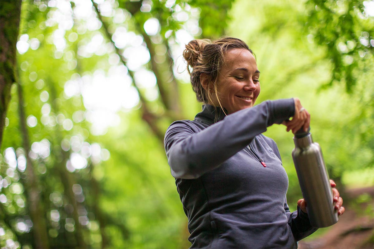 Woman In A Forest Drinking From A reusable water bottle