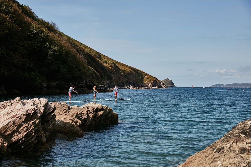 3 people paddling Red Original Paddle Boards in the sea