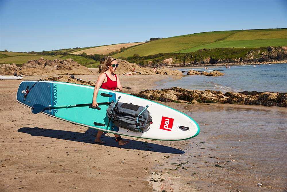 woman carrying her paddleboard into the sea