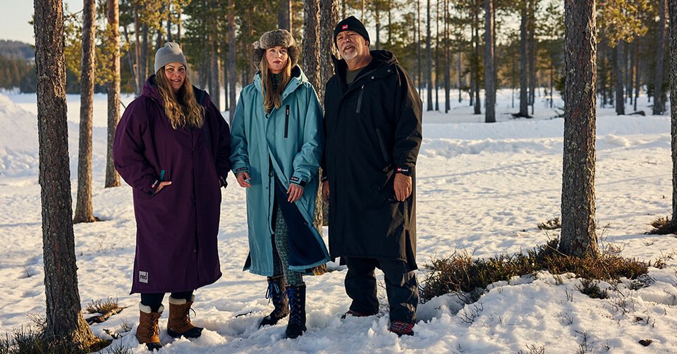 Three people wearing Red Original Pro changing robes in snowy woodland